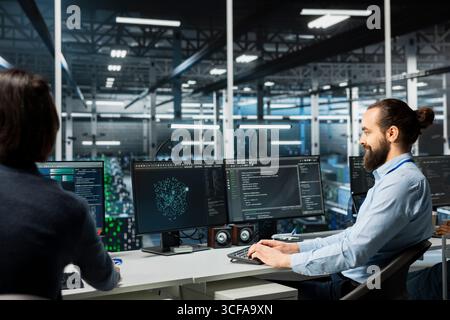 Data center system administrators monitoring AI systems, adjusting machine learning parameters. Server room admins enhancing artificial intelligence technology performance Stock Photo