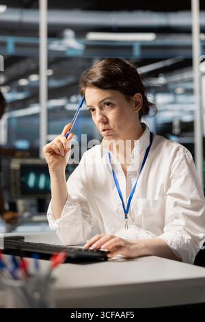 Data center technician doing brainstorming on how to fix gear, doing maintenance tasks. Server farm employee thinking how to repair network rigs after conducting system checks Stock Photo