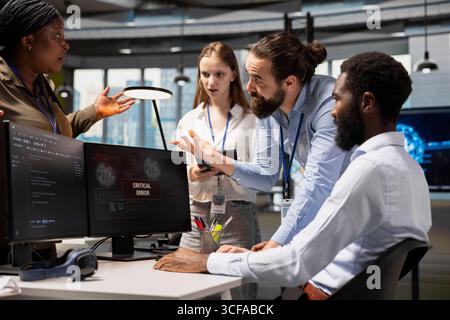 Software developers working together, resolving critical error alert on screen in tech startup office, troubleshooting system warnings. IT workers using PC to repair office equipment bugs Stock Photo
