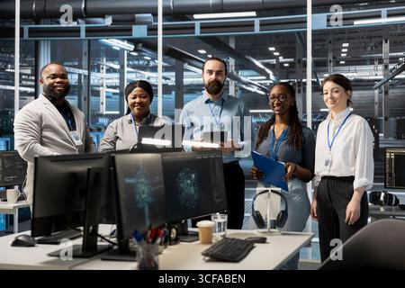Portrait of smiling engineering team working in server farm, analyzing data. Happy teamworking employees examining infrastructure in data center, ensuring system integrity and security Stock Photo