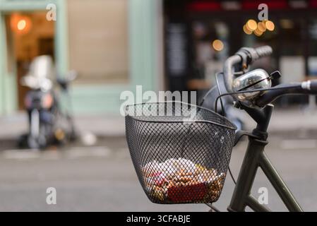 close-up of a bicycle with a basket filled with cigarette butts and trash in Paris Stock Photo
