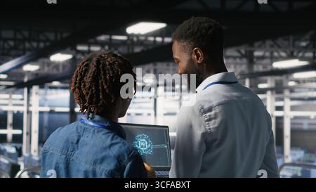Data center team on industrial platform collaborating to maintain servers using artificial intelligence. Engineers cooperating to support infrastructure AI machine learning automatization Stock Photo