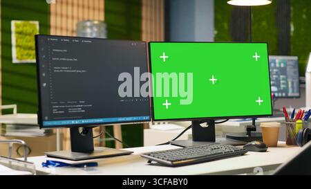 Mockup PC in empty IT startup office displaying programming languages used for building applications. Green screen computer showing code in software development agency with no people in Stock Photo