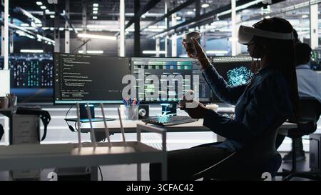 Server farm admin using VR equipment and node tree systems to categorize unstructured data. Data center IT specialist uses virtual reality headset and visual programming software, camera A Stock Photo