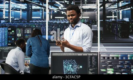 Data center technician uses node tree programming interface to identify equipment performance issues. Engineer reviews data analysis graph in server hub to minimize hardware failures, camera A Stock Photo