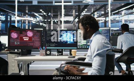 Overworked man in wheelchair upset by error warning popup while looking at server hub AI analytics metrics. Data center worker with disability irked by malfunction while using node tree tool, camera A Stock Photo