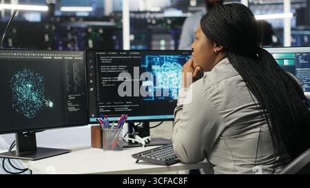 Data center admin does machine learning node tree programming, optimizing resource allocation. Server room worker uses predictive artificial intelligence visualization systems for maintenance, camera B Stock Photo