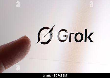 Close-up of Grok AI logo on screen with a finger pointing to the brand mark during AI platform comparison. Stafford, United Kingdom, August 21, 2025 Stock Photo