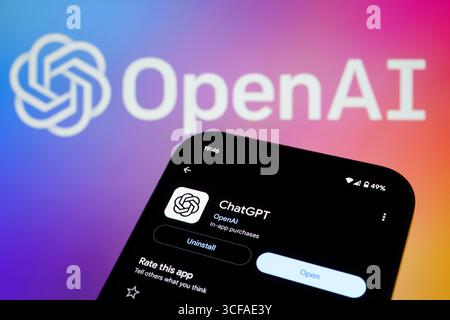 OpenAI branding behind ChatGPT app listing on smartphone showing Open button and rating in dark mode. Stafford, United Kingdom, August 21, 2025 Stock Photo