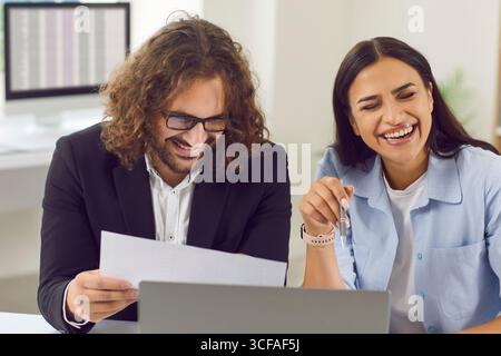 Two happy colleagues friends having fun and laughing at funny jokes at work in office Stock Photo