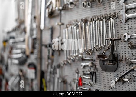 Assorted hand tools and socket wrenches neatly arranged on pegboard in workshop creating organized workspace for mechanical repairs and maintenance tasks  Stock Photo