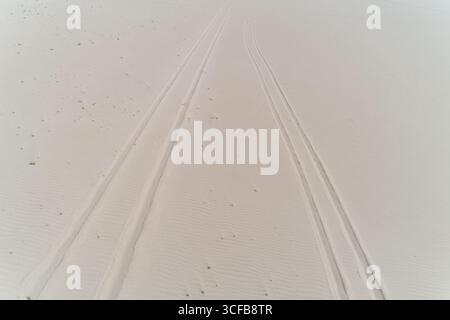 A sandy beach with two tire tracks in the sand Stock Photo