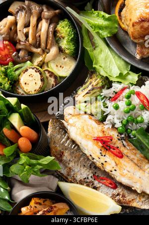 Various food of meat dishes, fish, salads, garnish and snacks on a black background. Top view. Stock Photo