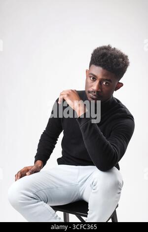Multiracial handsome brunette man posing in black turtle neck sweater against white background. Successful young man concept. Vertical shot Stock Photo