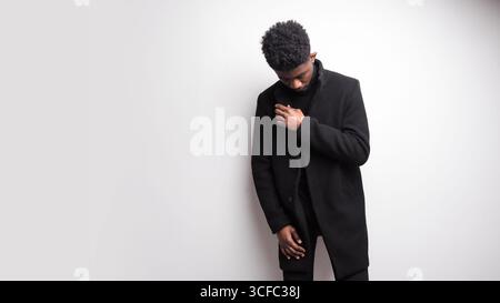 Serious young bearded guy in black clothes looking away while standing against white background. Human appearance concept Stock Photo