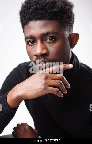 Portrait of pensive man looking at the camera, touching his chin, isolated over white studio background. Thoughtful guy thinking and making decision Stock Photo