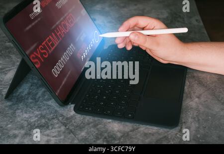 System hacked alert on laptop after cyber attack. Compromised information. Woman protecting data after cyber attack. Stock Photo