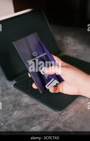 Smartphone screen displaying money transfer confirmation. Woman transfering money online using app on smartphone. Concept of financial transactions. Stock Photo