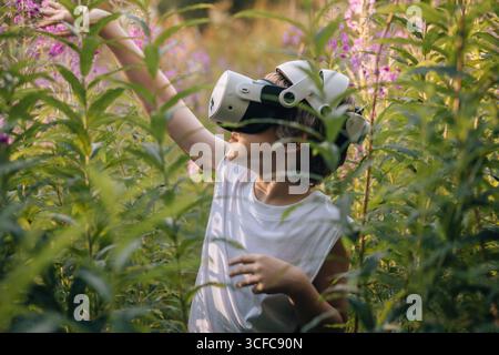 Man child in virtual reality glasses playing in tall grass Stock Photo