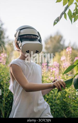 Man child in virtual reality glasses explores world in nature Stock Photo