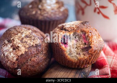 Two muffins on wood table with blurred background, one with berry filling visible. Stock Photo