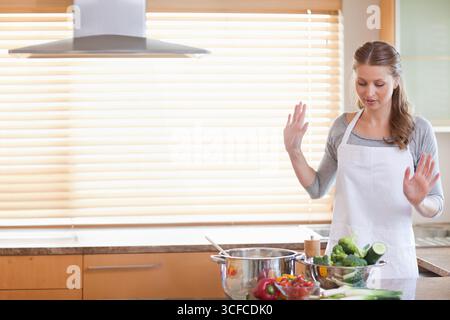 White home cook lifting and preparing vegetables in colander by pot in kitchen, copy space Stock Photo