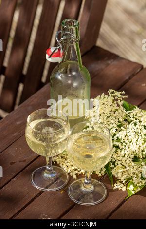 Sparkling Elderflower cordial and elderflowers outdoors in summer sunlight Stock Photo