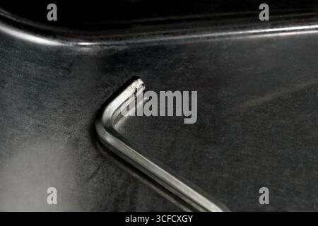 Craftsman uses a metal tool on a polished dark surface in a bright workshop. Stock Photo