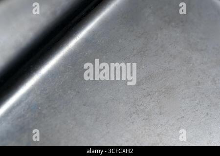 Dark brushed metal surface displays a unique texture with shadows and highlights. Stock Photo