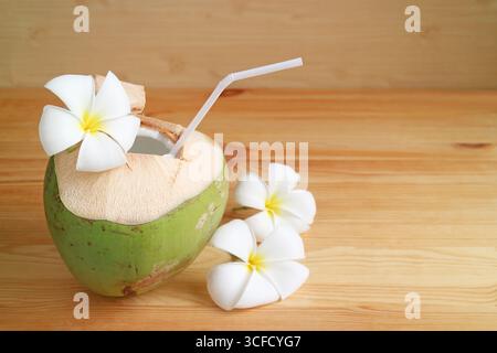Fresh natural young coconut juice in coconut shell isolated on wooden table Stock Photo