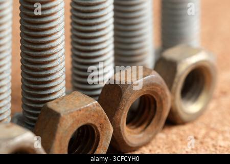 Close-up view of rusty nuts and bolts arranged neatly on wood, showcasing wear. Stock Photo