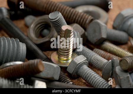A rich assortment of metal hardware parts resting on a wooden work surface. Stock Photo