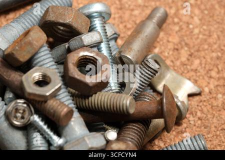 Screws, bolts, and nuts are arranged on a textured surface in an intricate display. Stock Photo