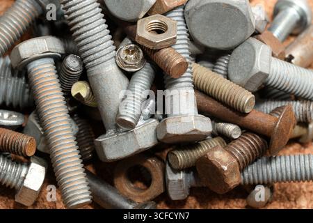 Various bolts, nuts, and screws mix on a gritty workbench, showcasing textures. Stock Photo
