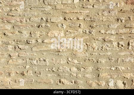 Wall of horizontally aligned gray stones held together with brown cement. Front view. Stock Photo