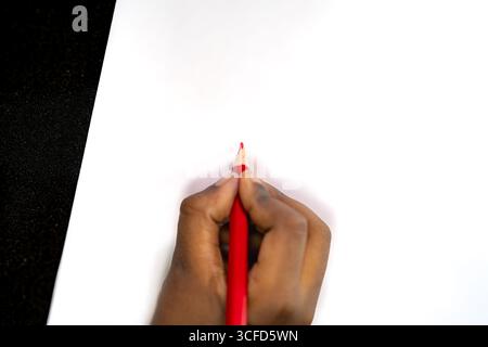 Hand Holding Red Colored Pencil on White Paper Stock Photo