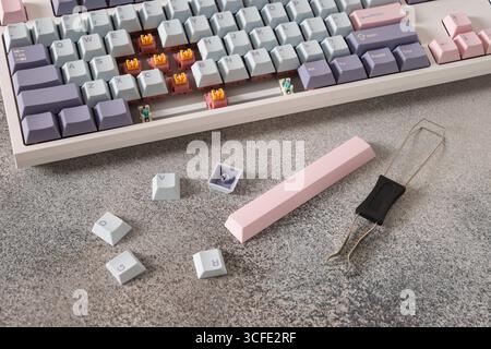 Concept cleaning keyboard. Mechanical keyboard with pastel keycaps on gray desk. Service. Changing, and cleaning buttons. Close up. Stock Photo