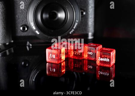 Doha, Qatar - August 22, 2025: Close-up of Red Photography Dice and Camera Lens on isolated background Stock Photo