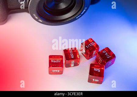 Doha, Qatar - August 22, 2025: Close-up of Red Photography Dice and Camera Lens on isolated background Stock Photo