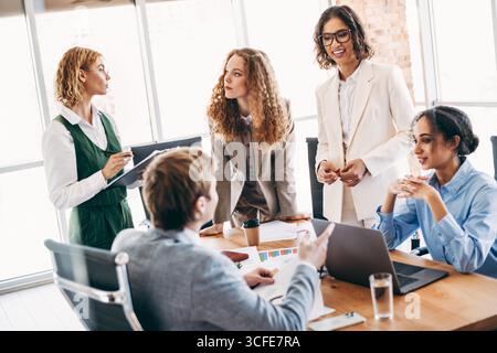 Professional team collaborating in office setting with diverse coworkers discussing work strategies and innovative solutions Stock Photo