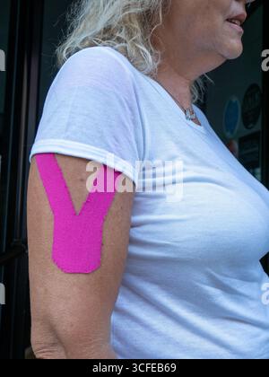 Woman's Upper Arm Shows Bright Pink Kinesiology Tape Applied For Muscle Support And Injury Recovery Treatment Showing Active Lifestyle And Health Cons Stock Photo