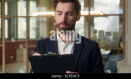 Caucasian thoughtful businessman middle-aged guy business man writing document in office male expert auditor broker real estate agent analyst thinking Stock Photo