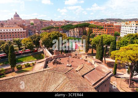 Panoramic view of Vatican City and Rome, with St. Peter Basilica dome and lush green trees in foreground Stock Photo