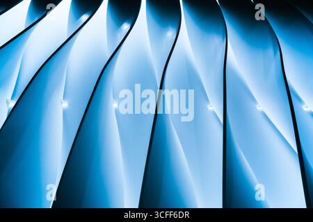 Ribbed wall with wavy stripes on it and blue backlighting in the middle. Stock Photo