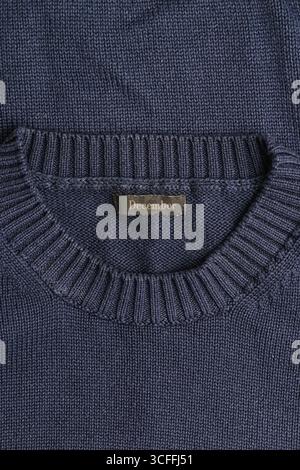 A close-up view of a blue knitted sweater featuring a ribbed neckline and a label with the word "December." The texture of the knit fabric is clearly Stock Photo