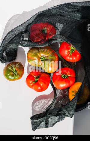 Ripe fresh Heirloom Tomatoes in Reusable Mesh Bag in natural light Stock Photo