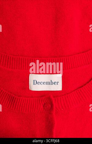 A close-up image of a vibrant red sweater featuring a label with the word "December", christmas concept Stock Photo