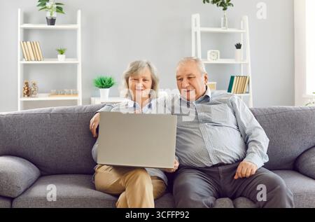 Happy Elderly Couple Using Laptop For Online Entertainment Stock Photo