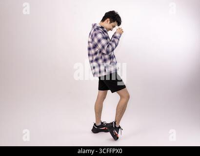young man adjusting glasses in a casual studio portrait setting Stock Photo