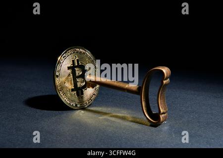 A physical Bitcoin with an old key, symbolizing the private key for a crypto wallet. A conceptual image for blockchain security, digital ownership, fi Stock Photo